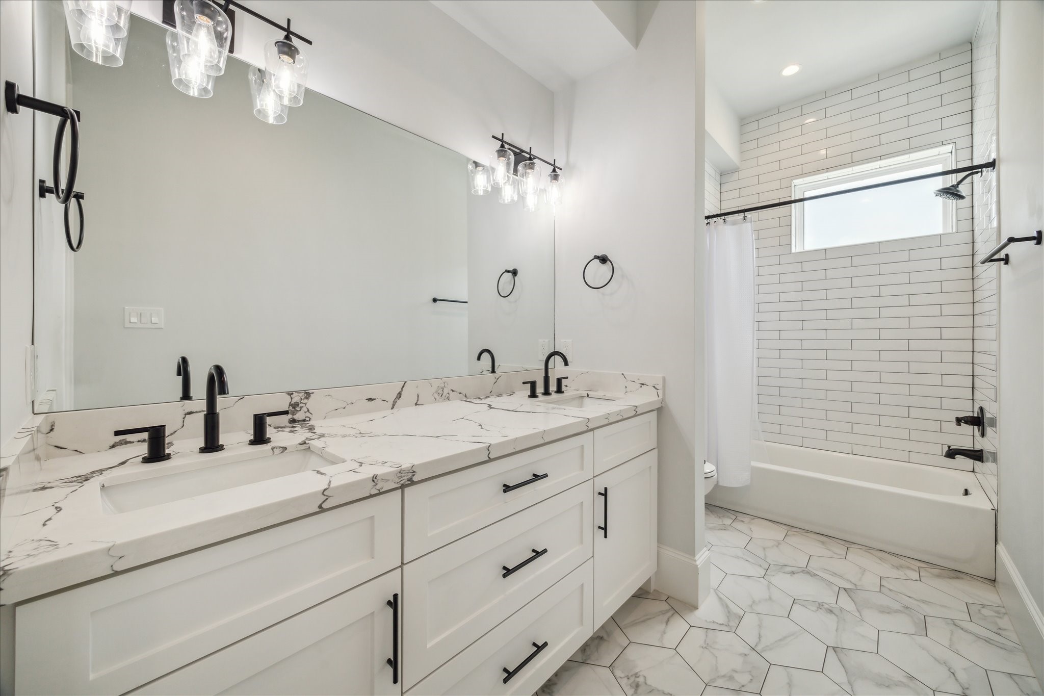 2202 Hewitt Drive Houston, TX 77018 - Photo 29 of 39 Second-floor hallway bathroom shared by two secondary bedrooms, featuring a double sink vanity, tub/shower combo, and sleek tile finishes throughout.