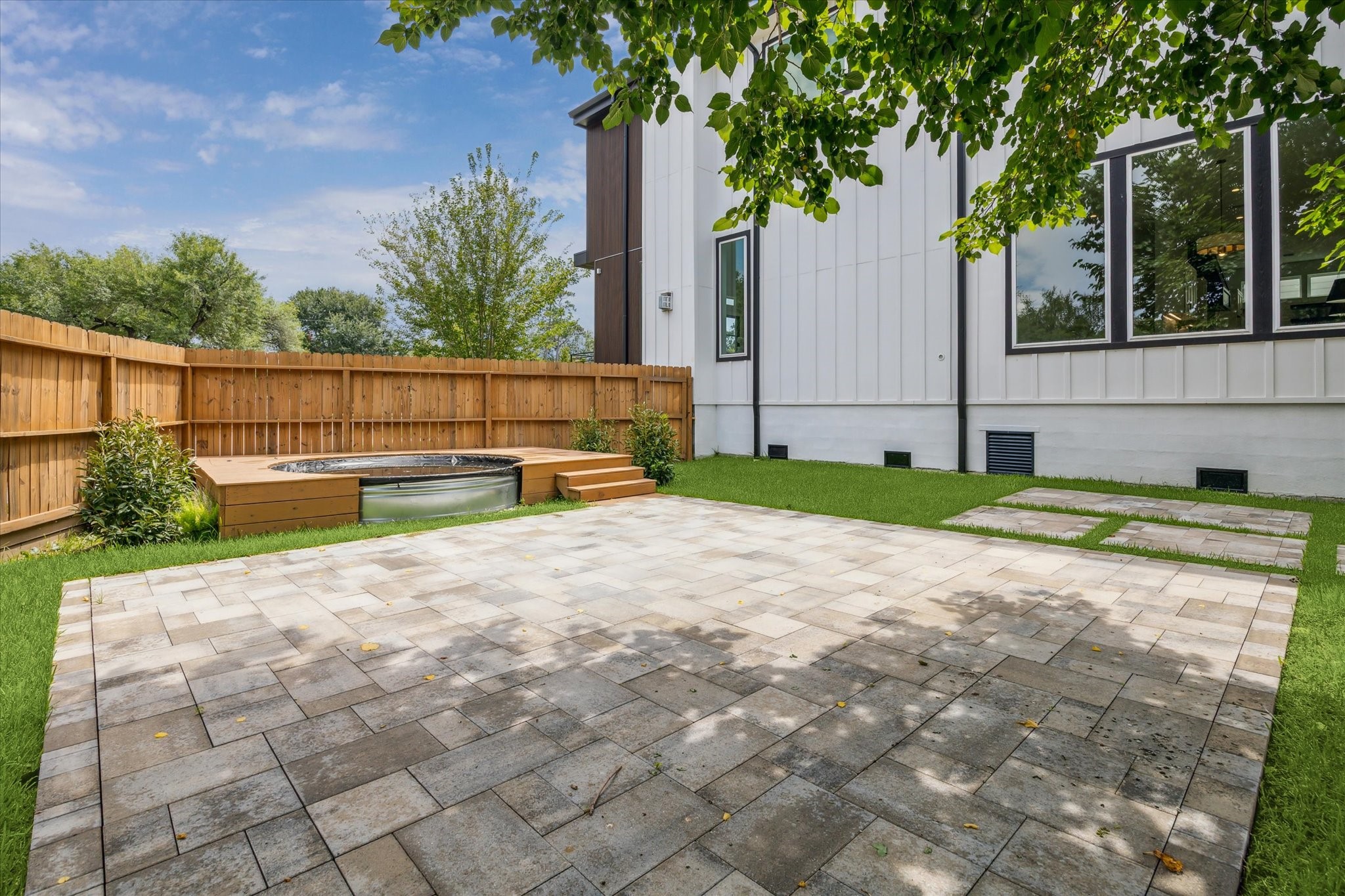 2202 Hewitt Drive Houston, TX 77018 - Photo 38 of 39 Paver pathway leading to an additional paver patio area, complemented by an above-ground stock tank pool with a stained wood deck surround.