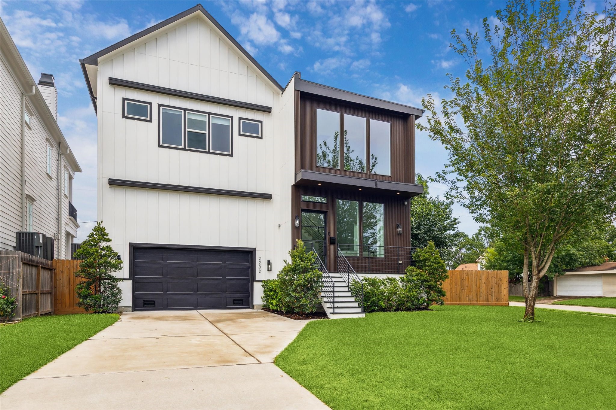 2202 Hewitt Drive Houston, TX 77018 - Photo 6 of 39 The exterior showcases a striking modern farmhouse design with clean, sleek lines. The front yard features mature landscaping on a spacious corner lot.
