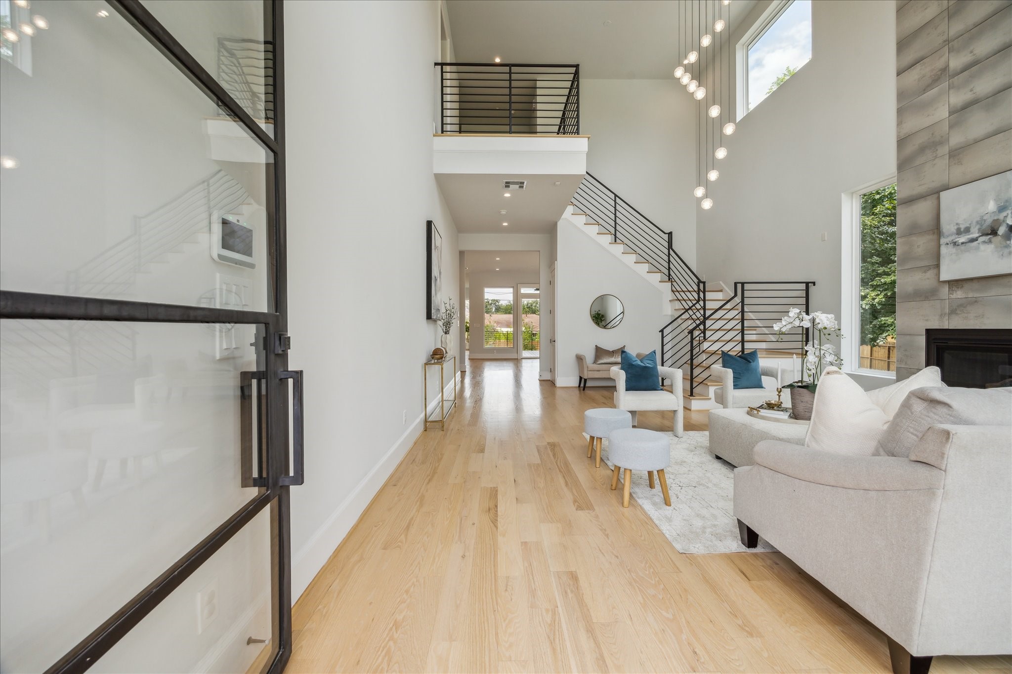 2202 Hewitt Drive Houston, TX 77018 - Photo 7 of 39 Upon entering, you’ll immediately notice the striking two-story, 23-foot ceilings in the front living room, featuring floor-to-ceiling windows that flood the space with natural light. Crisp neutral walls, light hardwood floors, and a sleek modern stairwell banister complete the bright, airy atmosphere.