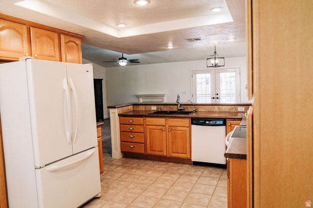 1825 West Mathis Park Place, Unit 40 St. George, UT 84770 - Photo 25 of 28 Kitchen featuring white appliances, a tray ceiling, dark countertops, a ceiling fan, and a peninsula
