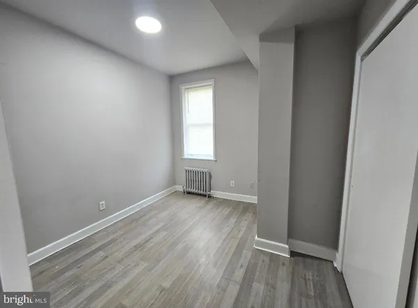 an empty room with wooden floor and window