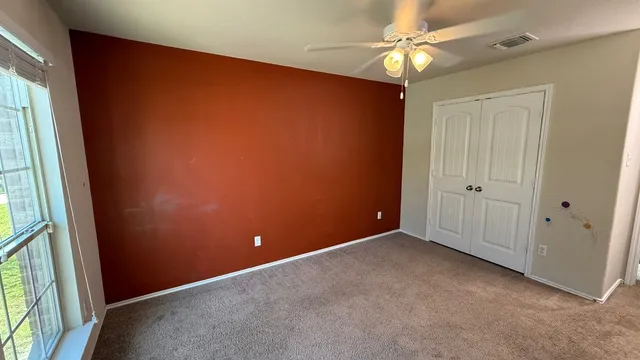 an empty room with a window and a fan