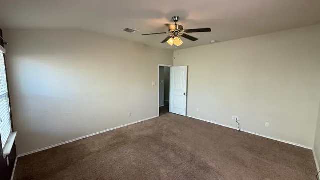 a view of an empty room and a chandelier fan