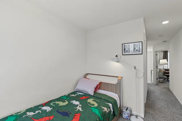 a bedroom with a bed and a lamp on dresser