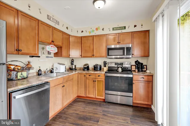 a kitchen with stainless steel appliances granite countertop a stove a sink dishwasher and a microwave oven with wooden floor