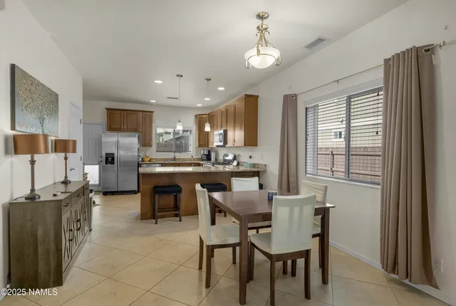 a kitchen with a dining table chairs and refrigerator