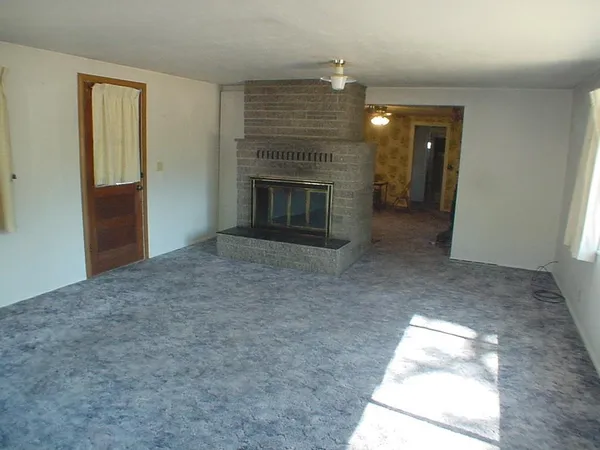 an empty room with windows and fireplace