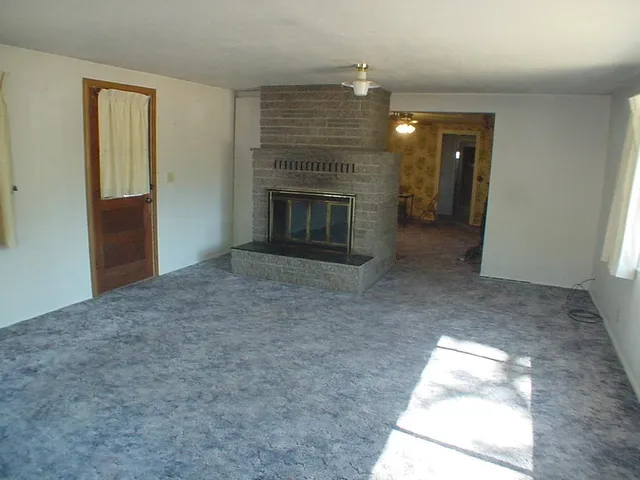 an empty room with windows and fireplace