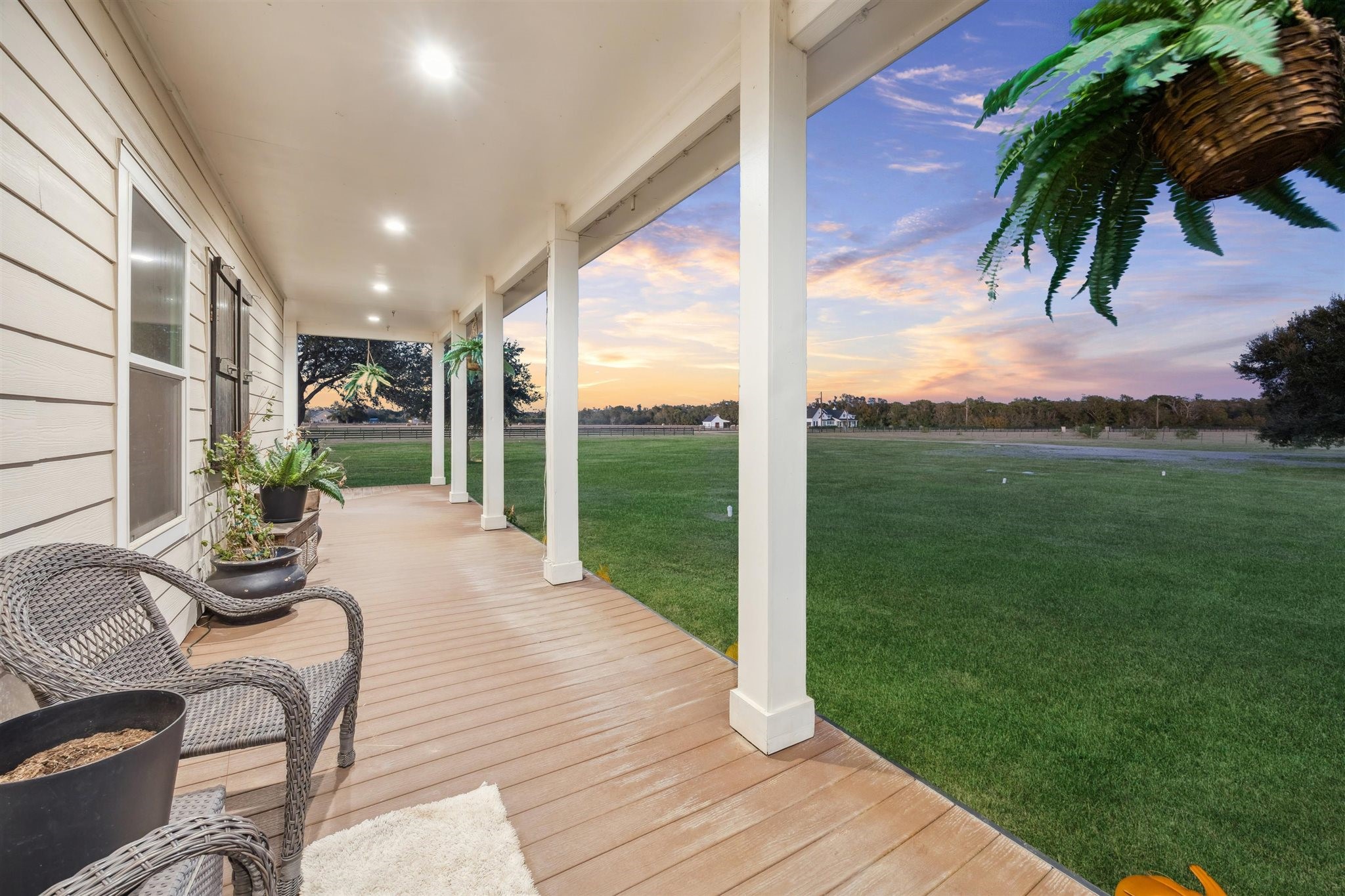 40570 Wildlife Run Hempstead, TX 77445 - Photo 33 of 43 A peaceful escape, this long side porch offers a shaded walkway lined with wicker chairs, potted ferns, and serene country views. With recessed lighting above and an open lawn stretching out beyond, it’s a perfect place to greet the sunrise or say goodnight to the day on land. The property is a wildlife exemption, adding both beauty and value to the land.