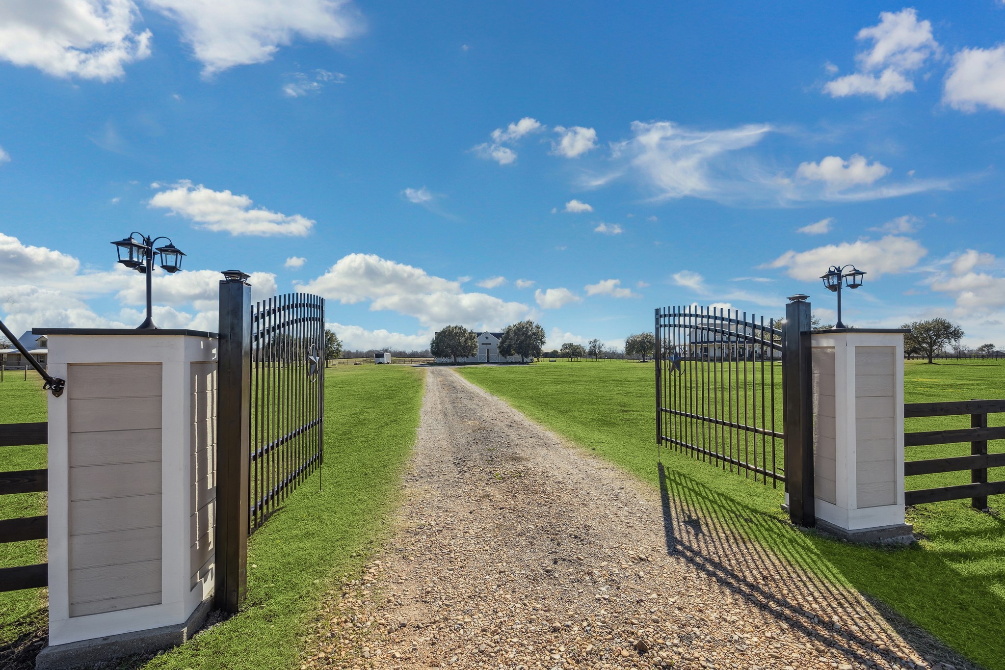 40570 Wildlife Run Hempstead, TX 77445 - Photo 36 of 43 A grand Texas welcome this gated entry sets the tone for your private ranch estate. The dual iron gates, flanked by lantern-lit pillars, open to a long gravel drive lined with lush green pasture, leading to the heart of this nearly 19-acre equestrian property. Security and style meet in a setting where the land holds a wildlife exemption, reflecting its purpose, care, and connection to nature.