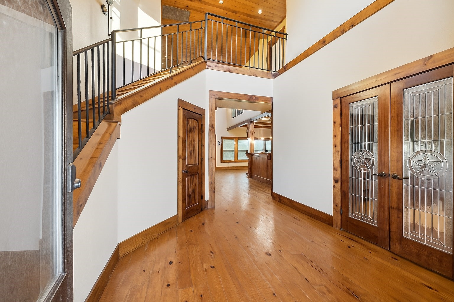 40570 Wildlife Run Hempstead, TX 77445 - Photo 5 of 43 Step into a warm, wood-accented foyer with soaring ceilings, rustic railings, and detailed woodwork. Double glass doors with star-inlay design open into a home filled with Texas character, welcoming guests into a lifestyle of relaxed sophistication. Virtually decluttered to help visualize potential use.