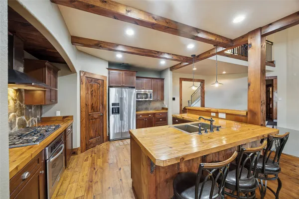 a kitchen with stainless steel appliances kitchen island granite countertop a table chairs stove and refrigerator