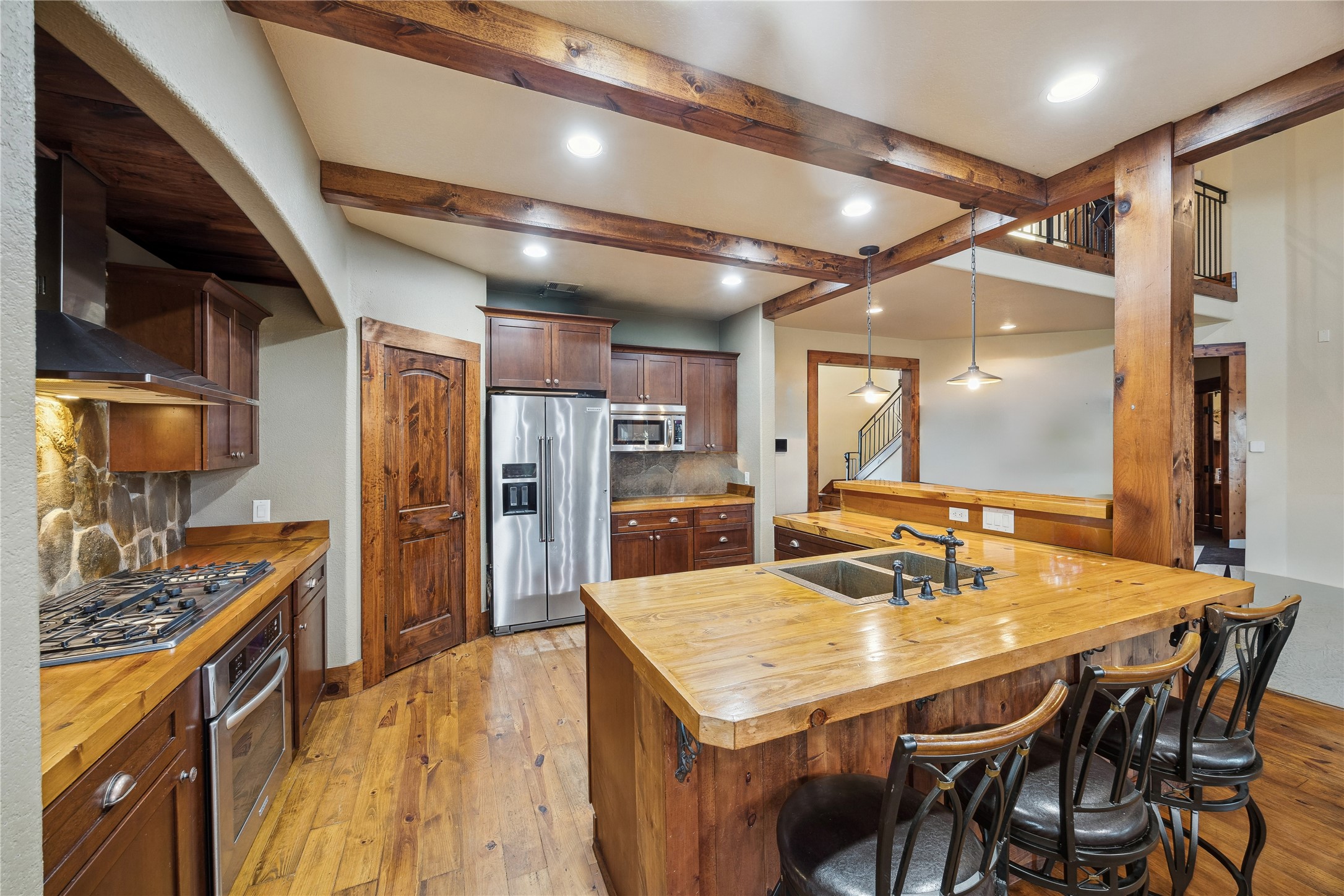 40570 Wildlife Run Hempstead, TX 77445 - Photo 10 of 43 A large butcher-block island anchors this kitchen, offering abundant prep space and bar-style seating. Surrounded by stainless steel appliances, stone backsplash, and natural wood details, the kitchen is both timeless and totally functional. Virtually decluttered to help visualize potential use.