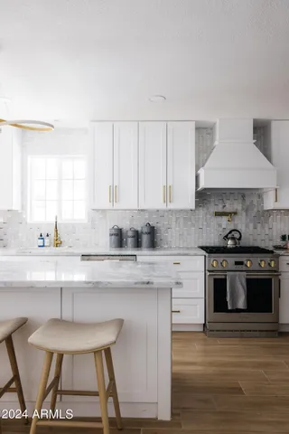 a kitchen with granite countertop a sink chairs and refrigerator