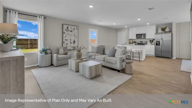 a kitchen with stainless steel appliances granite countertop a stove a refrigerator a sink a dining table and chairs