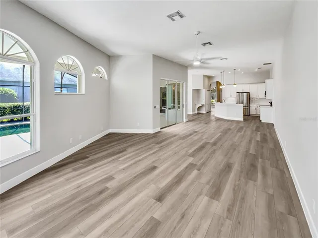 a view of empty room with wooden floor and fan