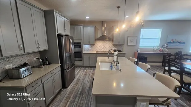 a kitchen with stainless steel appliances a dining table chairs refrigerator and cabinets