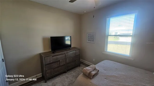 a bedroom with a bed and a flat tv screen on a dresser