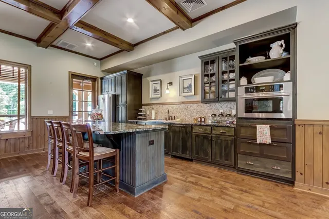 a kitchen with stainless steel appliances kitchen island granite countertop a table chairs and a refrigerator