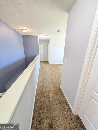 a view of a hallway with wooden floor and a bathroom