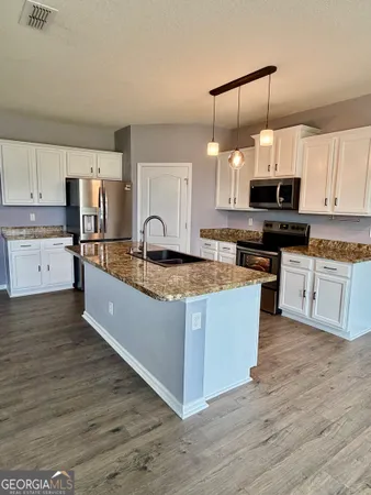 a large kitchen with stainless steel appliances granite countertop a stove a sink dishwasher and a refrigerator