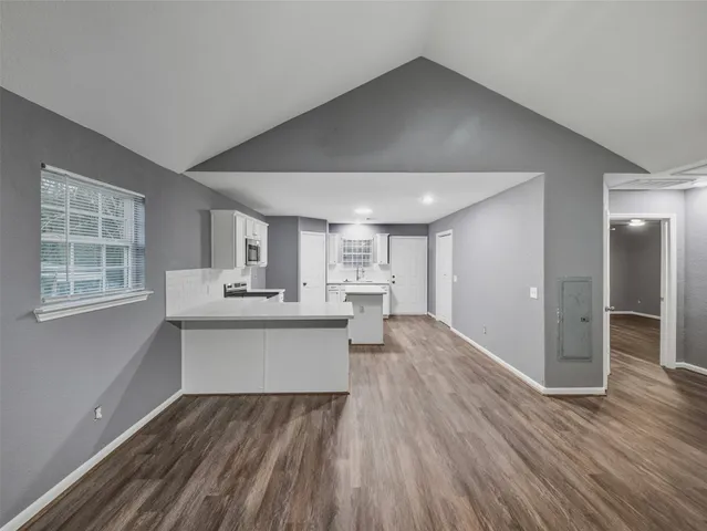 a view of a kitchen with kitchen island a sink wooden floor and counter top space