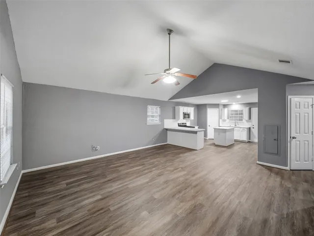 a view of a room with wooden floor a ceiling fan and window