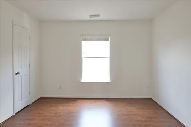 an empty room with wooden closet and windows