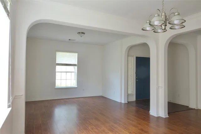a view of a room with wooden floor chandelier and windows