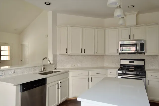 a kitchen with appliances a sink and cabinets