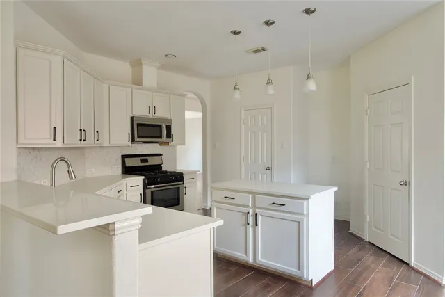 a kitchen with white cabinets and stainless steel appliances
