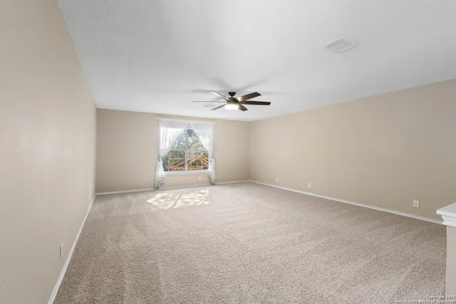 an empty room with windows and ceiling fan