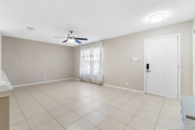 an empty room with chandelier fan and windows