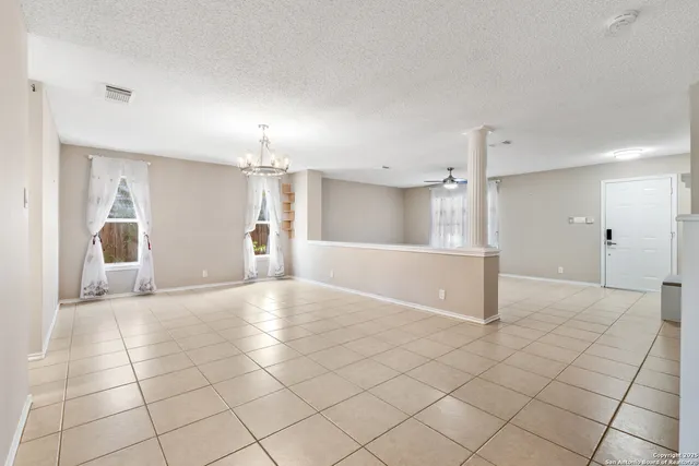 an empty room with kitchen and chandelier fan