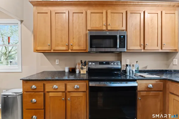 a kitchen with granite countertop a stove a sink and a microwave