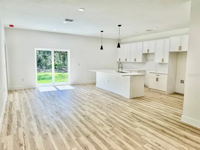 a large white room with kitchen island a sink wooden floor and living room view