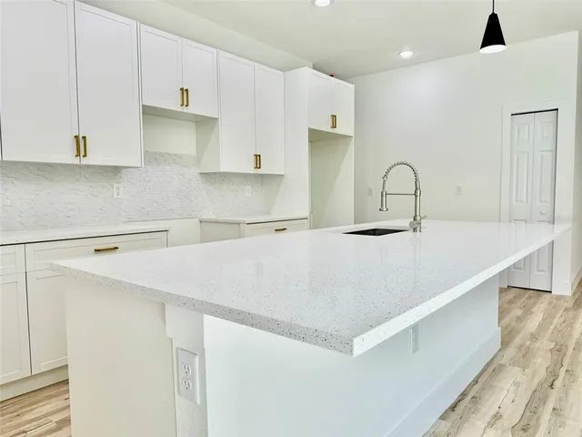 a kitchen with stainless steel appliances a sink a stove a refrigerator with white cabinets