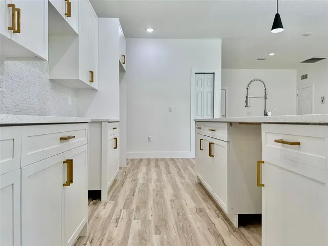 a kitchen with white cabinets and wooden floor