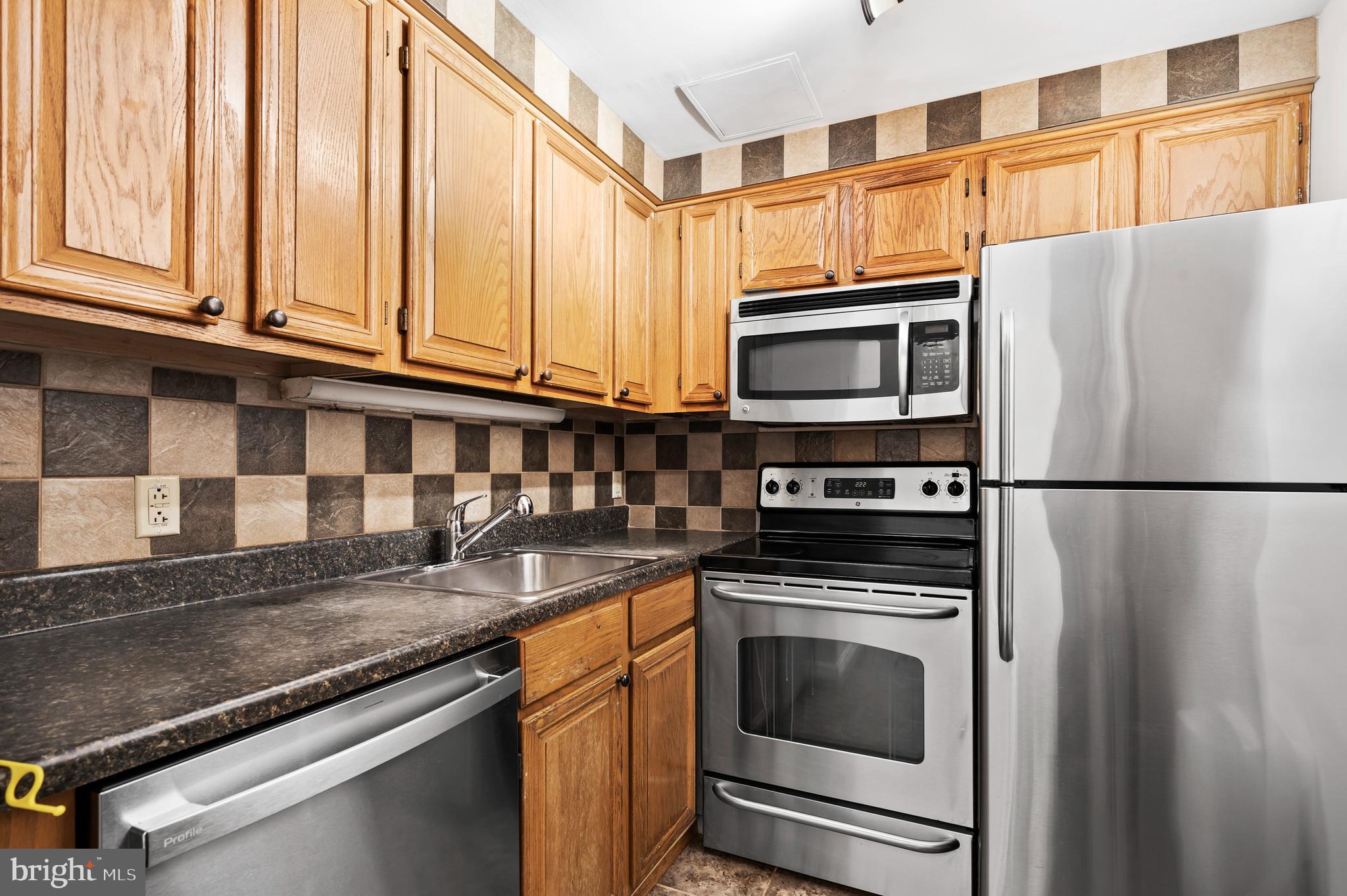 136 North Bread Street, Unit 130 Philadelphia, PA 19106 - Photo 9 of 31 a kitchen with granite countertop a refrigerator stove and microwave