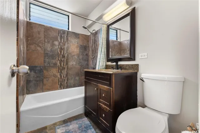 a bathroom with a granite countertop bathtub sink vanity mirror and toilet