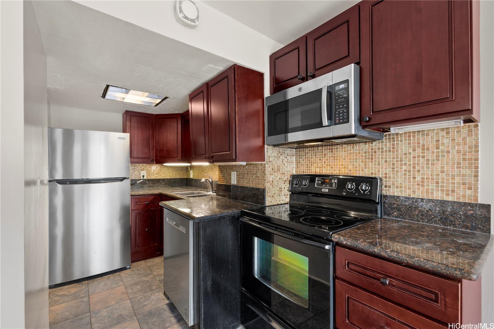 440 Seaside Avenue, Unit 404 Honolulu, HI 96815 - Photo 10 of 21 a kitchen with granite countertop wooden cabinets stainless steel appliances and a granite counter tops