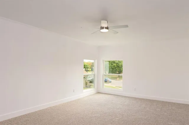 an empty room with a window and a ceiling fan