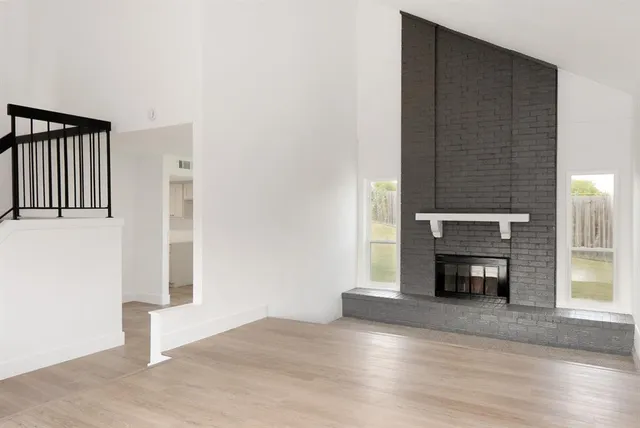 an empty room with fireplace and wooden floor