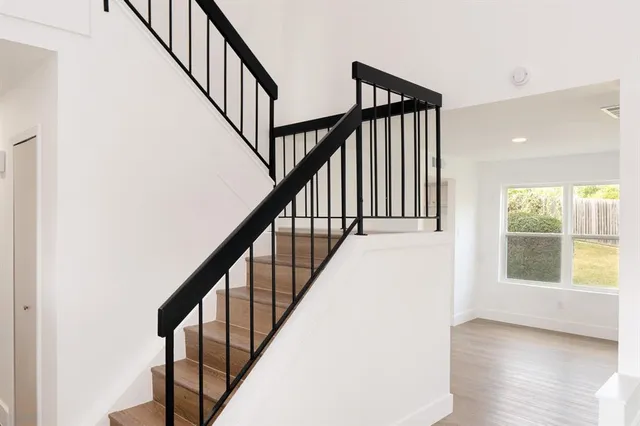 a view of staircase with wooden floor and white walls
