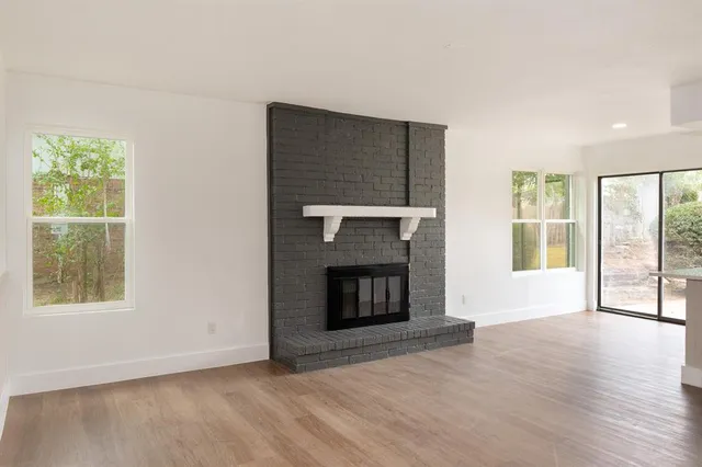 a view of an empty room with a window and fireplace