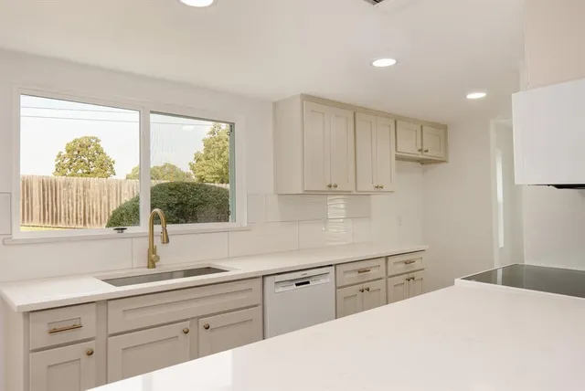 a kitchen with white cabinets a sink and a window