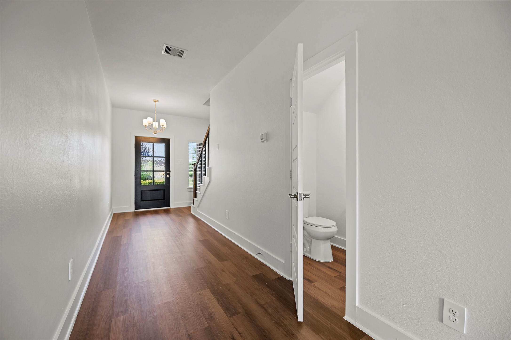 10603 Whitejacket Conroe, TX 77385 - Photo 4 of 42 Bright and airy entryway with laminate wood flooring, leading to a staircase. Features a modern chandelier and a conveniently located half-bathroom.