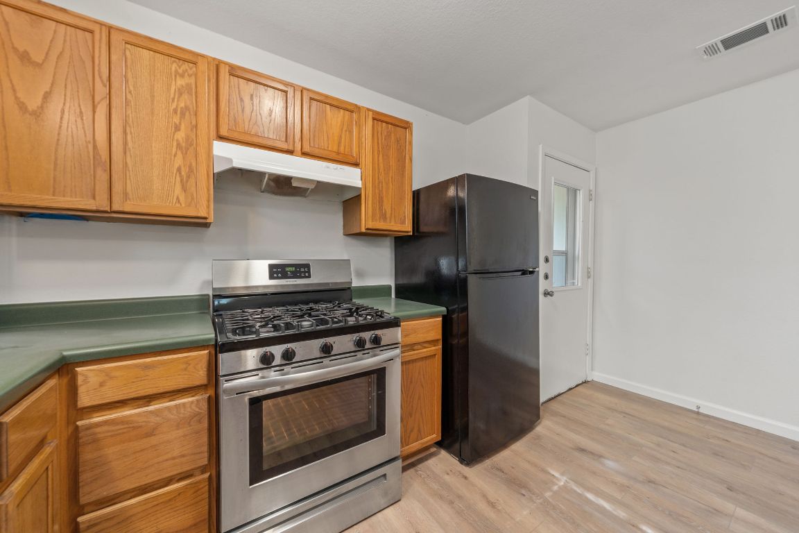1804 Singleton Avenue Austin, TX 78702 - Photo 15 of 36 a kitchen with stainless steel appliances granite countertop a stove top oven a refrigerator and cabinets with wooden floors