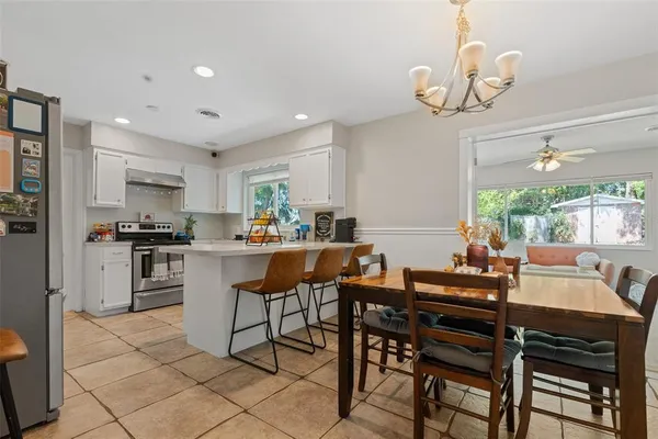 a kitchen with a dining table chairs stainless steel appliances and cabinets